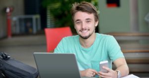 male college student with phone and laptop