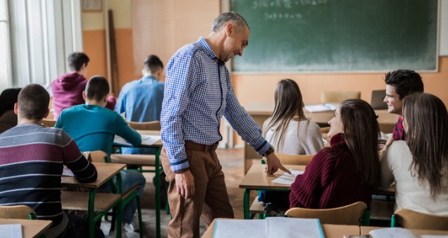 Teacher walks around classroom helping students