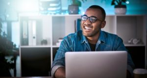 Man smiles while typing on computer