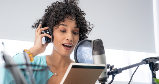 Student holds up notepad to ask questions over podcast microphone