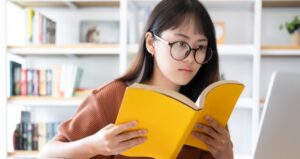 Student looks through book while taking exam