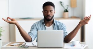 Student takes deep breath while at computer and meditates