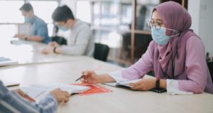Students work at tables while socially distant and wearing masks