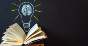 Book with chalkboard and lightbulb with brain drawn on it