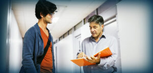 Student talks to professor in hallway