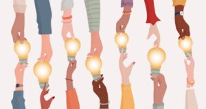 Hands holding a lightbulb with diverse individuals