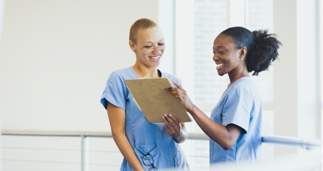 Two student nurses talk and smile with each other