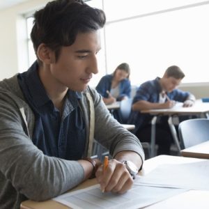Student takes exam at desk with other students